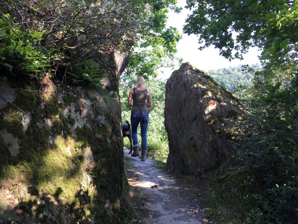 Frau mit Hund zwischen Felsen auf dem Nette-Schieferpfad