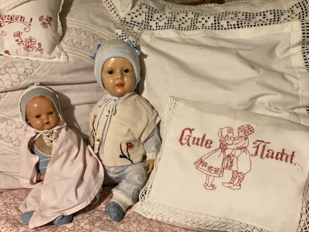 Zwei Puppen neben besticktem Kissen